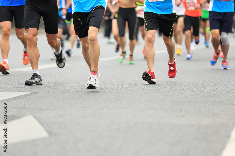 Unidentified marathon athletes legs running on city road