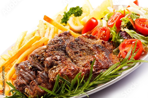 Grilled steak, French fries and vegetables on white background 