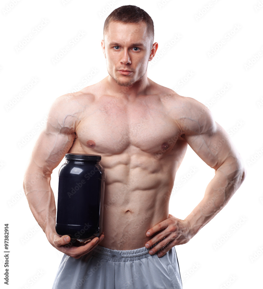 Bodybuilder holding a black plastic jar with whey protein isolated on white background