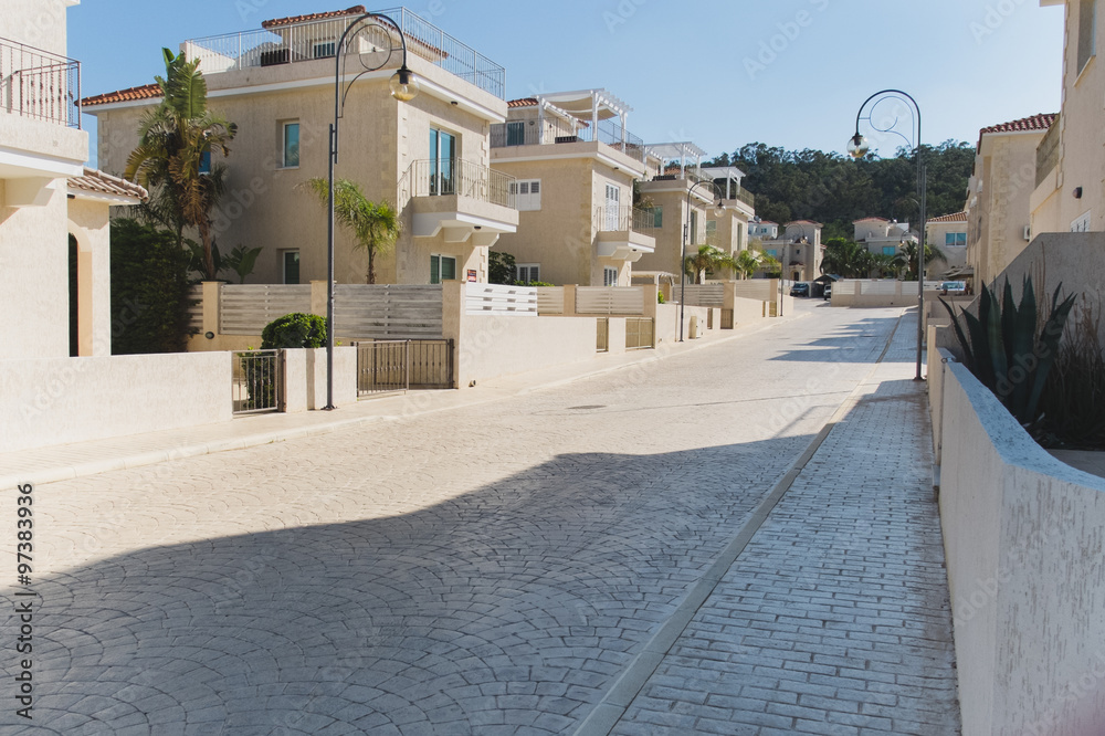 Fototapeta premium Street with pavement trees and white houses with red tile