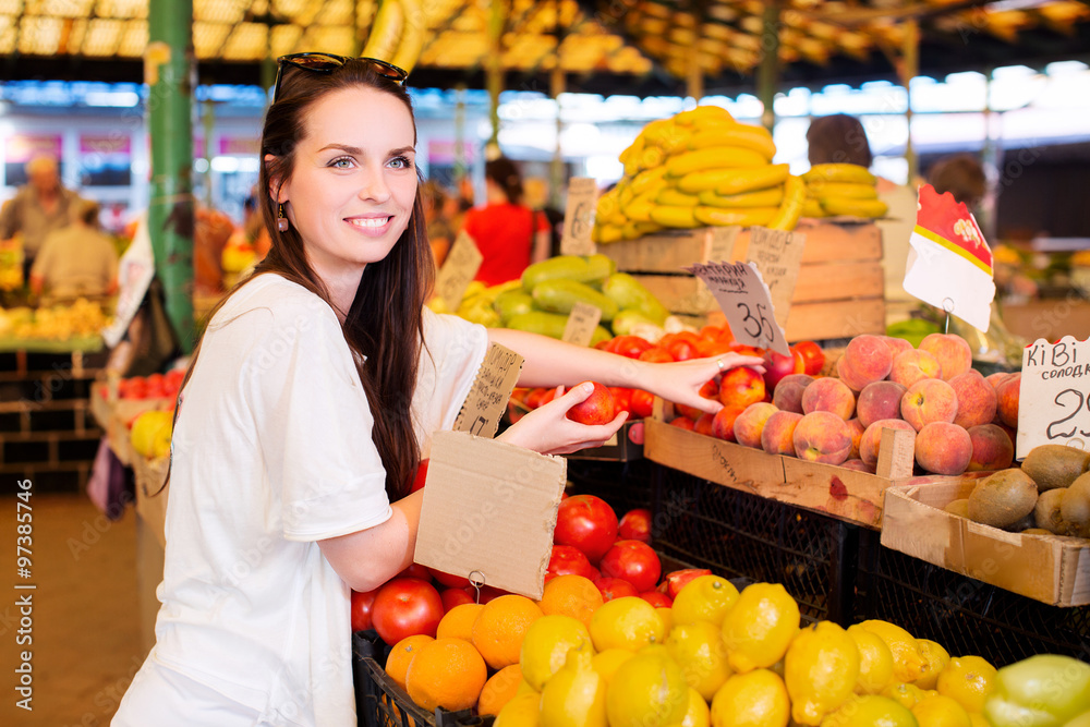 Young smiling woman is holding fresh nectarines during shopping