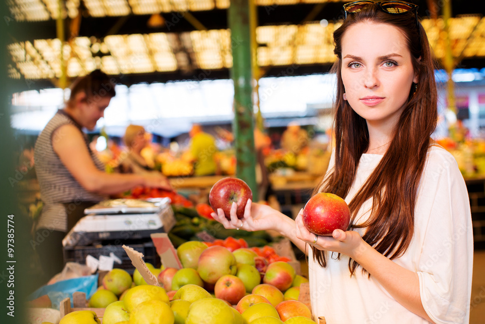 Beautiful young woman, wearing in white t-shirt, is holding two apples in her hand Beautiful young woman, wearing in white t-shirt, is holding two apples in her hand