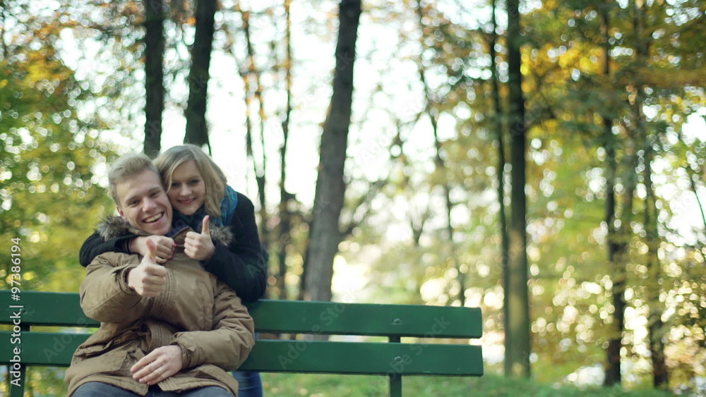 Couple cuddling and showing thumbs to the camera in the park
Couple cuddling and showing thumbs to the camera in the park