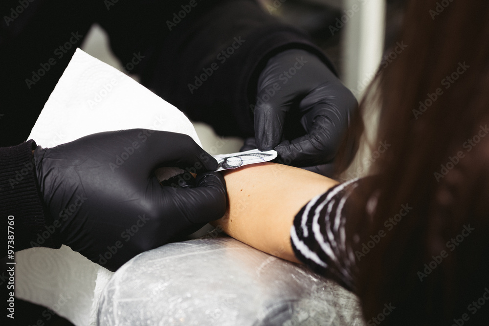 Tattoo master on back jacket and gloves is preparing for making tattoo