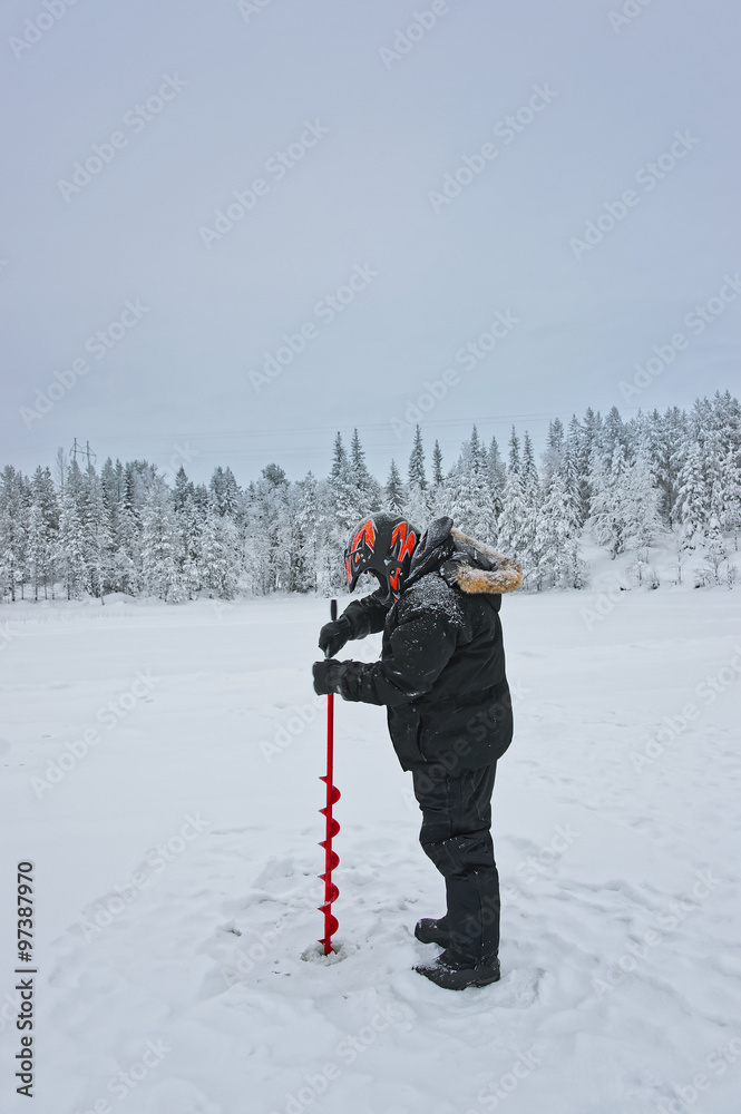 Man is drilling ice-hole for ice-fishing in Ruka in Lapland