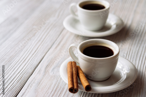 Two cups of espresso on a white wooden table