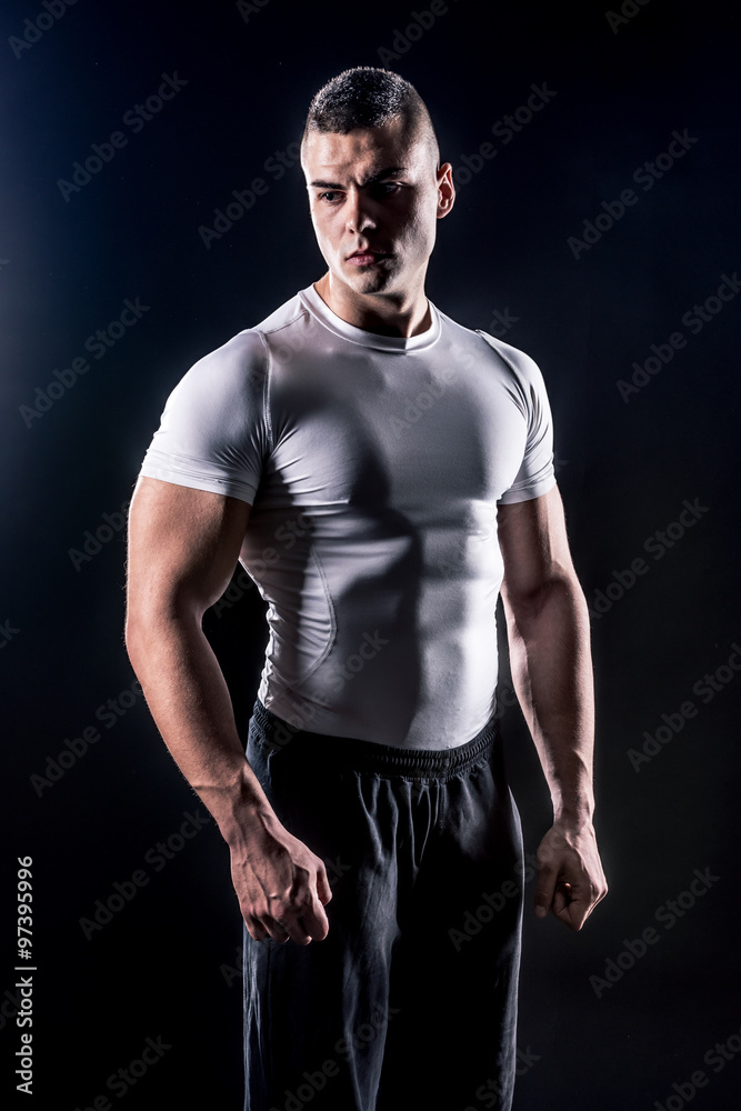beautiful male athlete in white shirt isolated over black background beautiful male athlete in white shirt isolated over black background