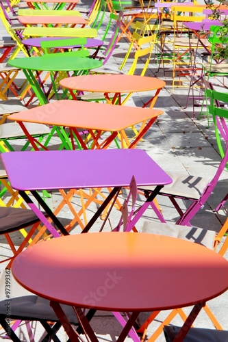 Des tables rondes et carrées de toutes les couleurs sur une terrasse en extérieur photo