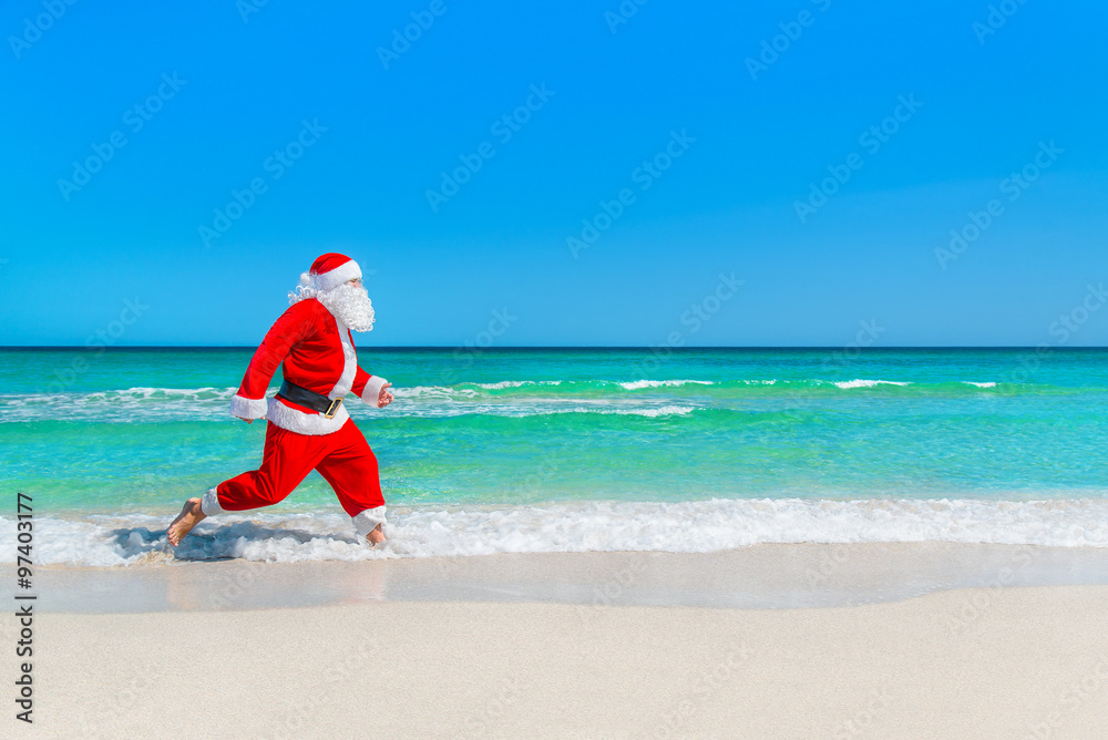 Christmas Santa Claus running at tropical beach on waves splashe