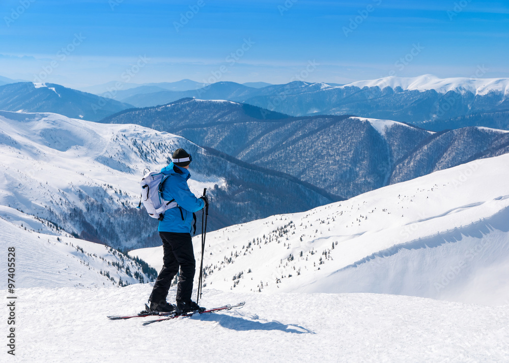 Skier in alpine skis go skiing in snowy mountains landscape