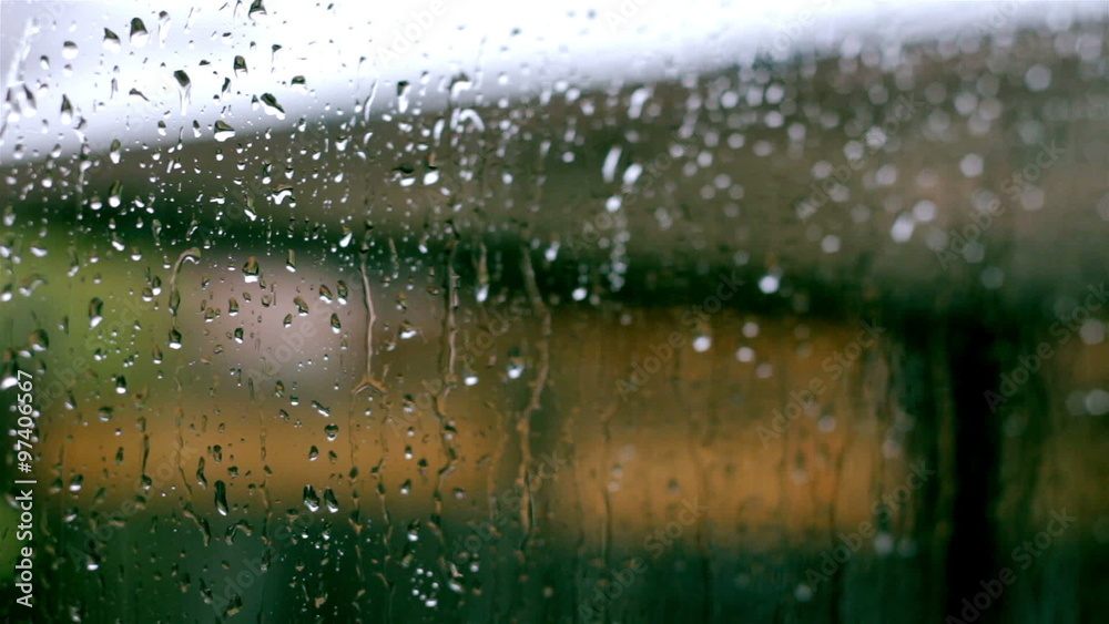 Closeup of raindrops streaming down a glass window pane
