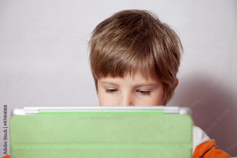 A boy who is engaged with a tablet computer A boy who is engaged with a tablet computer