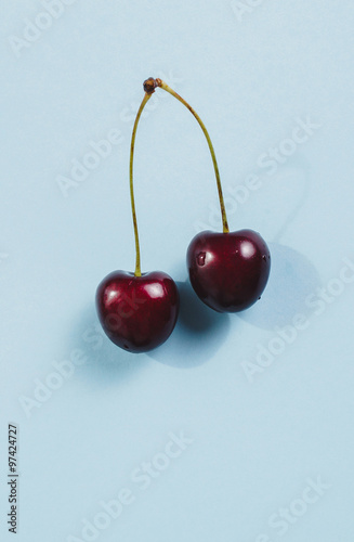 Two ripe cherries on blue background