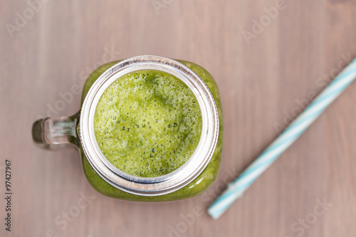 A green smoothie in a mason jar with tube 