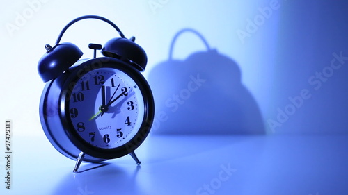 Classical twin bell alarm clock on the bedside table at night - copy space