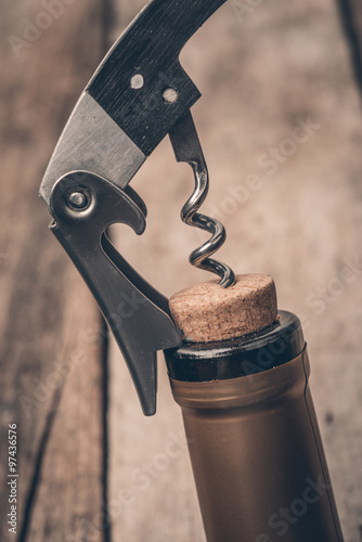 Cork screw and wine bottleOpening a wine bottle with a corkscrew in a restaurant photo