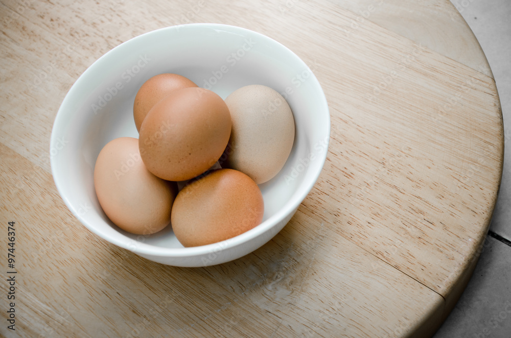 the five eggs in white ceramic bowl on wood table the five eggs in white ceramic bowl on wood table