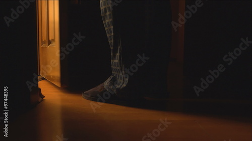 An adult man walking to a bathroom at the night and opens the door
 photo