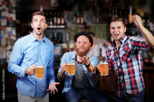 Young men with beer rejoice the victory of their favorite team in the pub