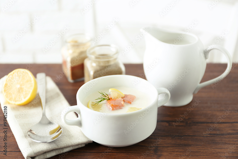 Delicious salmon cream soup on wooden table, which served with sliced lemon and spices Delicious salmon cream soup on wooden table, which served with sliced lemon and spices