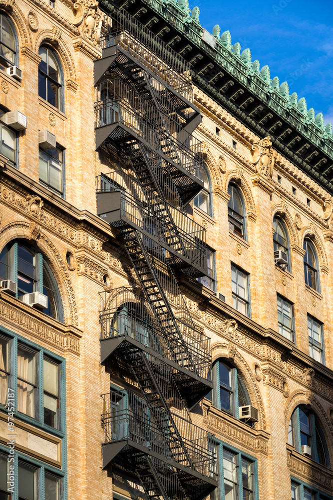 Typical late 19th century Soho brick building with fire escape, ornate facade and copper cornice. Manhattan, New York City