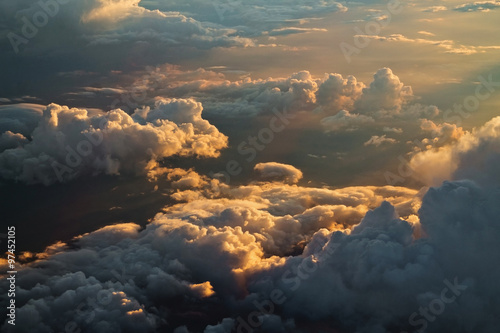 view from the airplane at the clouds, illuminated by the setting sun