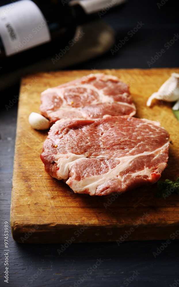 Marbled beef steak with bottle of wine and spices on wooden background Marbled beef steak with bottle of wine and spices on wooden background