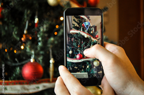 Hand taking photo of Christmas tree by smartphone