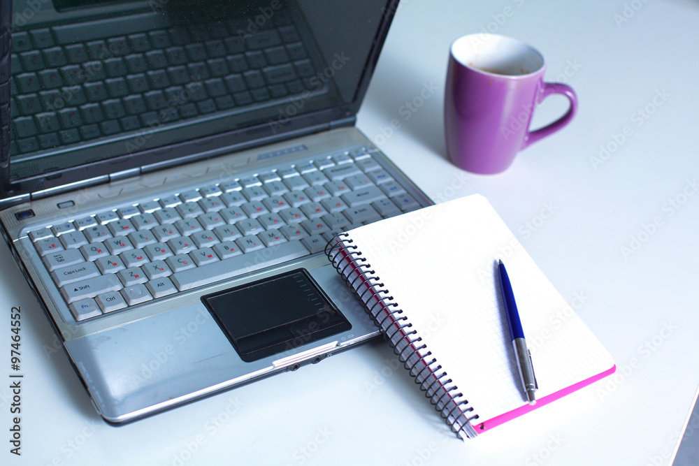 Office table with blank notepad and laptop Office table with blank notepad and laptop