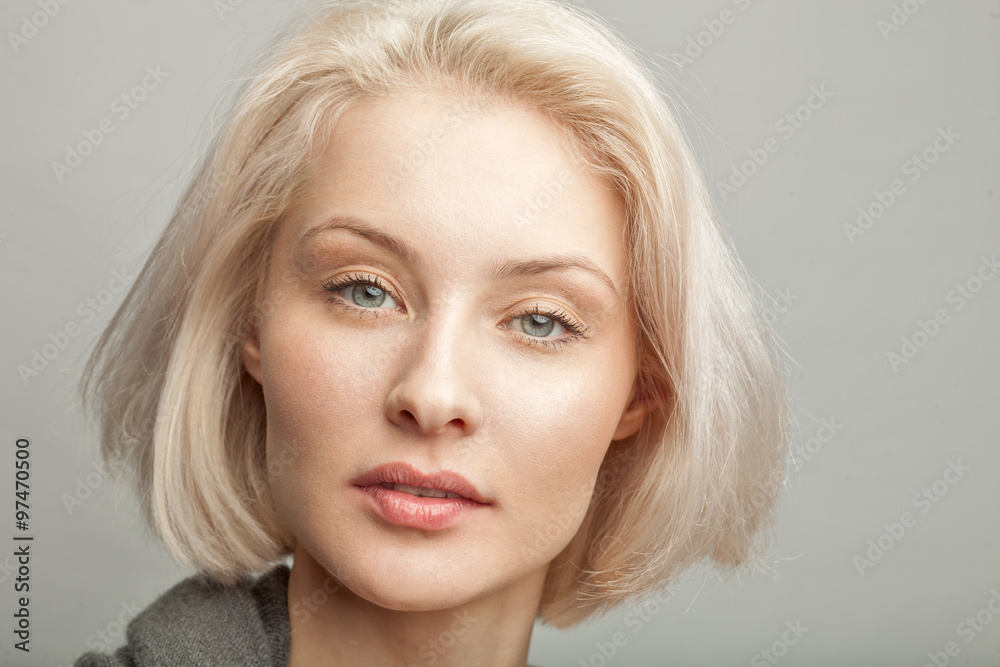 Naklejka premium artistic portrait of young blonde woman on gray background