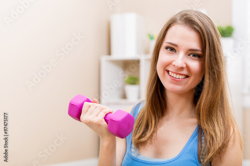 Happy young woman working out with dumbbells