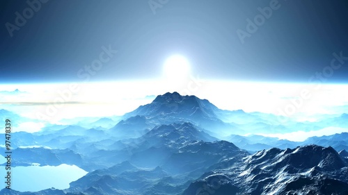 Sunrise over the mountain peaks. A thick white mist and clouds cover the blue mountains. From - for the horizon the sun slowly rises white. The entire landscape in white and blue colors.