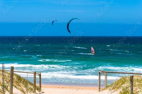 Ocean beach with kite and wind surfers in a distance photo