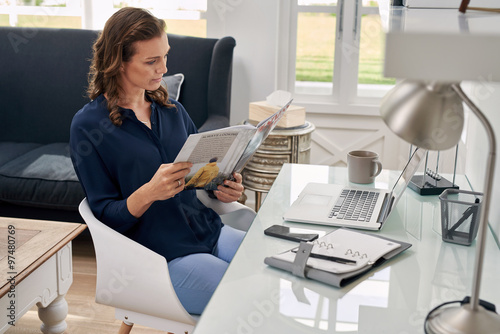 woman reading business magazine at home office desk