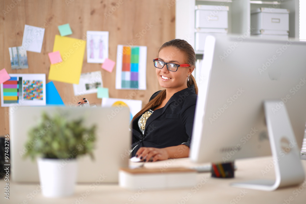 Fashion designers working in studio sitting on the desk