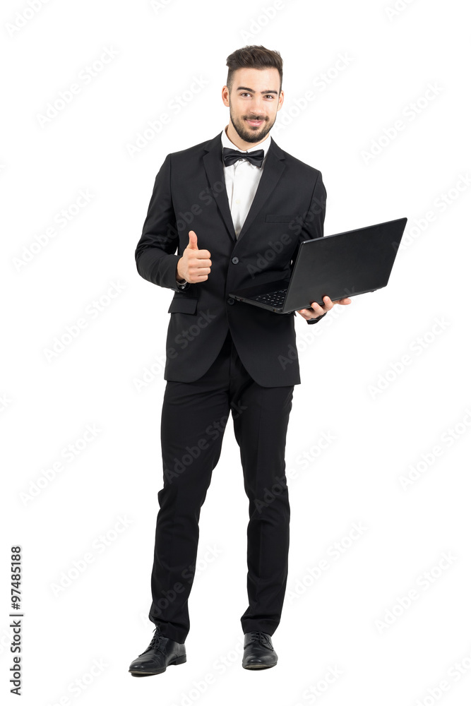 Young businessman with laptop showing thumbs up o.k. hand sign gesture. Full body length portrait isolated over white studio background. Young businessman with laptop showing thumbs up o.k. hand sign gesture. Full body length portrait isolated over white studio background.
