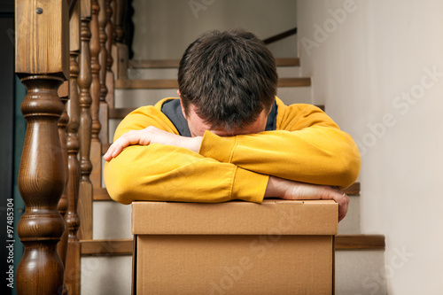 Moving house. Young man with cardboard boxes on a stairs. photo