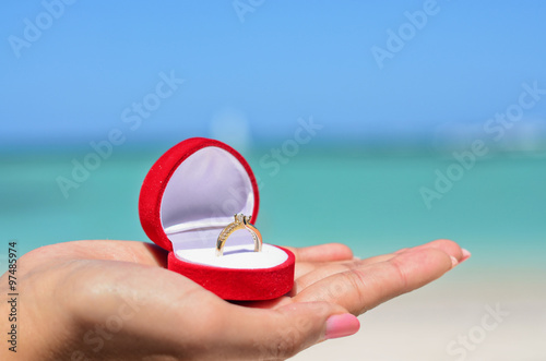 Fotografia Female hand holding golden wedding ring in red jewellery box on