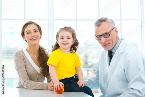 Aged doctor with little patient in hospital office
