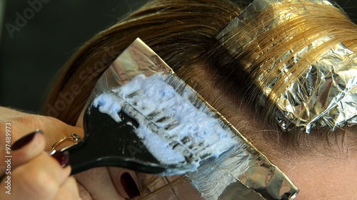 Applying lightener with the hairdressing brush to the locks of hair on the foil. Professional hair coloring process. 
