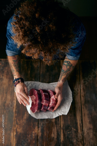 Very top view curly head butcher packing steaks in paper