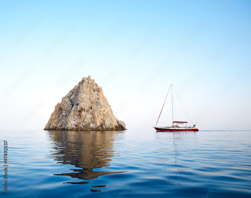 sailing yacht next to a rock in the sea