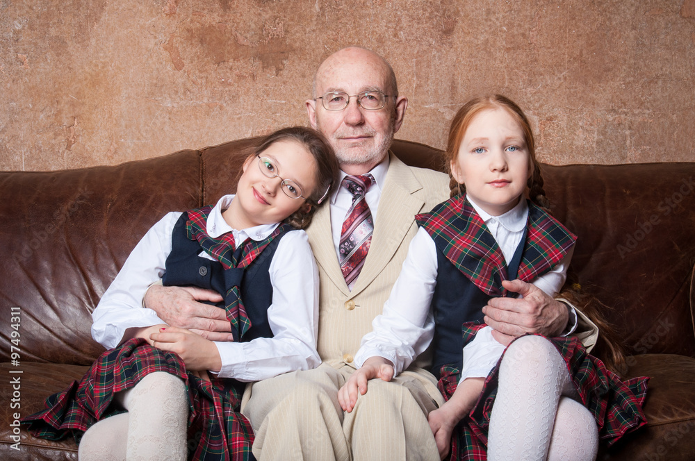 Дед и две внучки обнимаются и улыбаются в костюмах