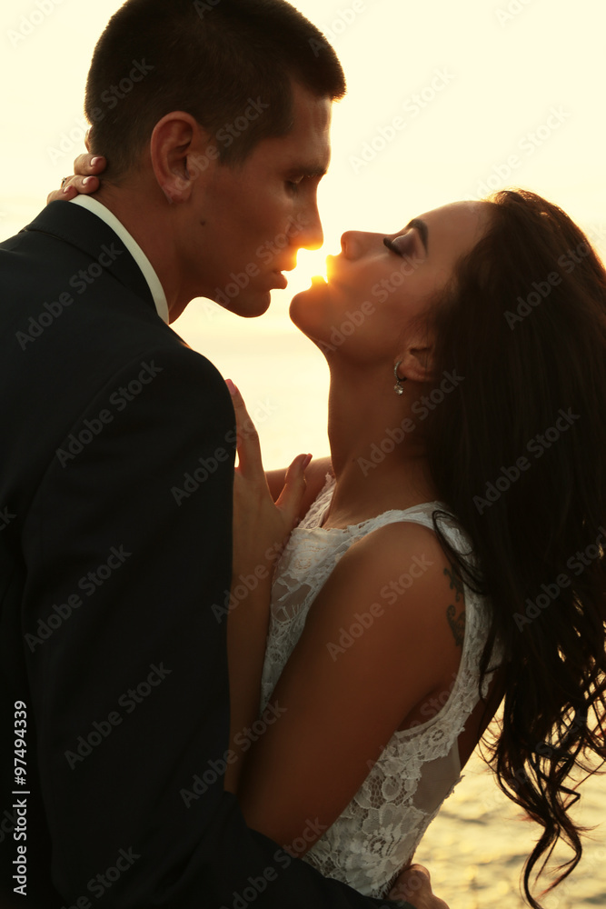beautiful groom and bride in wedding clothes posing on sea coast beautiful groom and bride in wedding clothes posing on sea coast