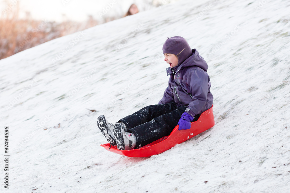 Naklejka premium Child playing with sled in winter snow