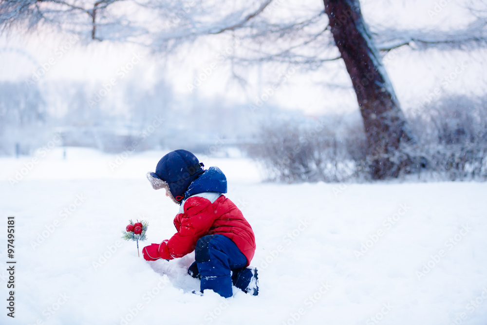  Adorable toddler boy having fun with snow on winter day