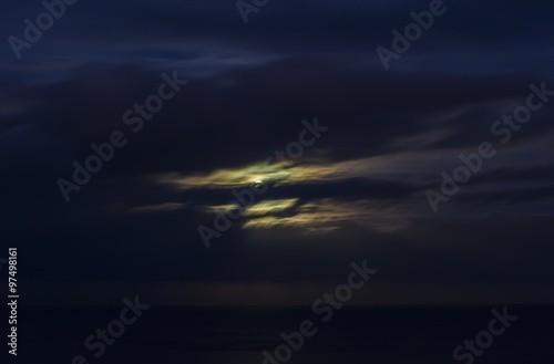 Moon shining in cloudy night sky.