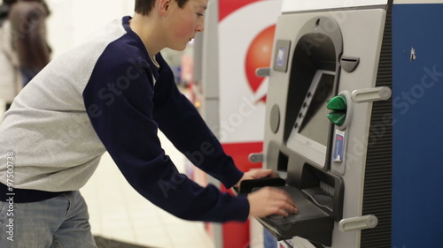 Teen inserts bank card into the ATM and enters PIN