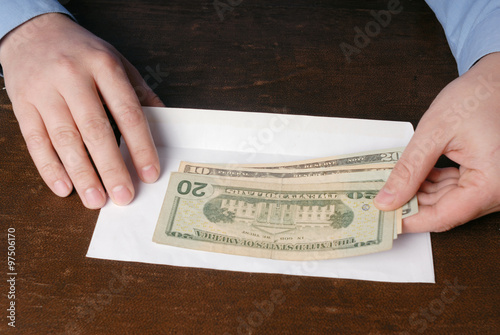 Pair of male caucasian hand holding USA dollars and white envelo photo