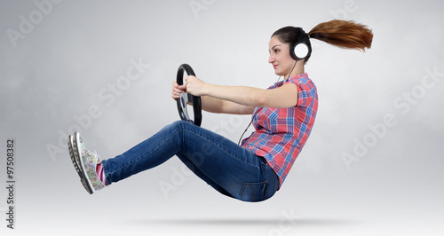 Beautiful girl in headphones driver car with a wheel, auto concept